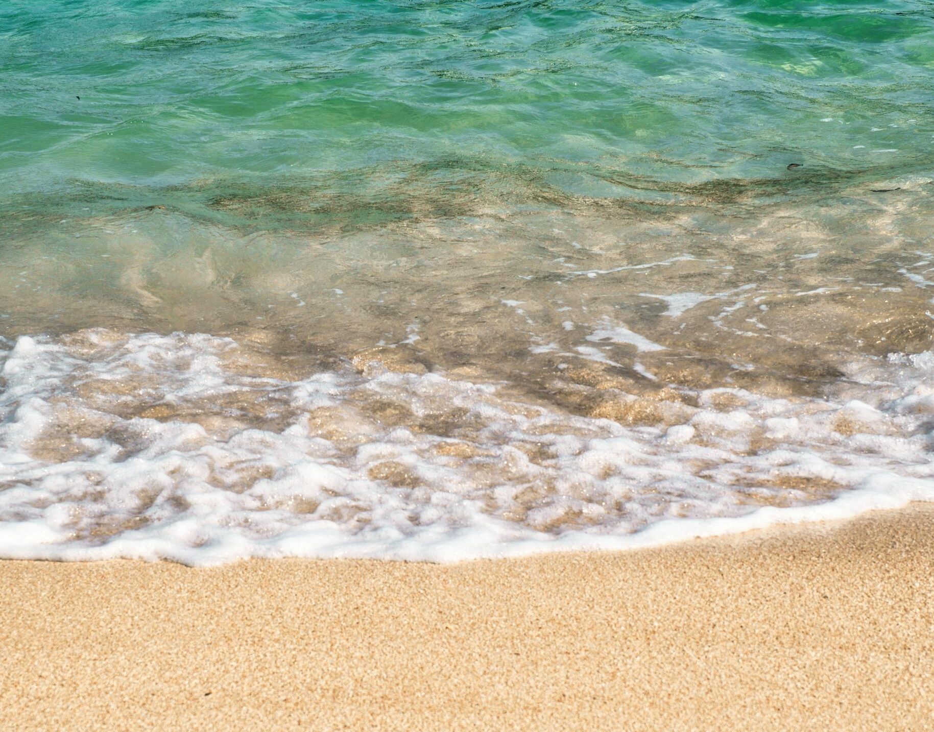 Calming waves on a sandy beach in Naha, Okinawa, Japan, showcasing the vibrant summer sea.