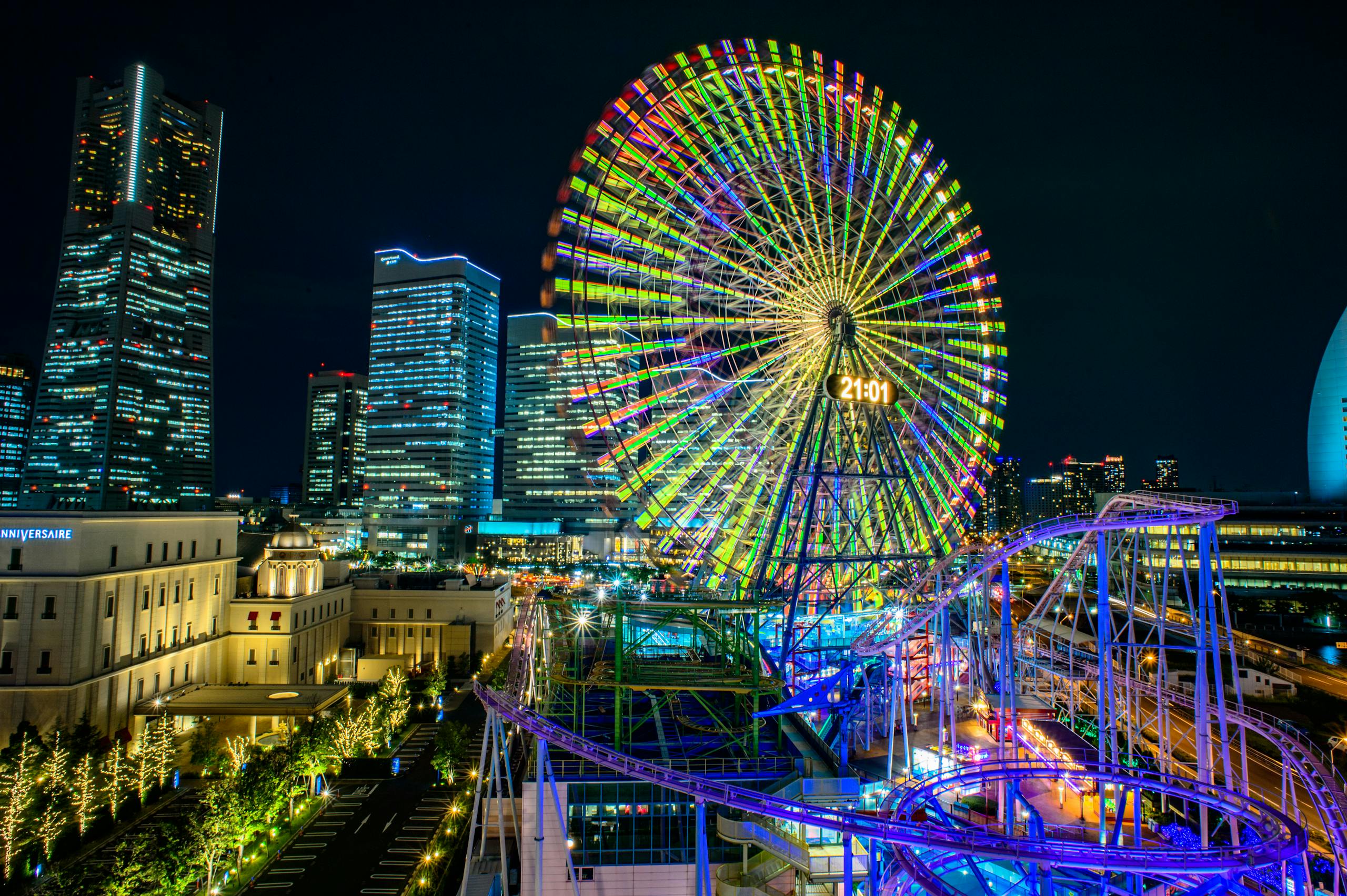 Vibrant night view of Yokohama's Cosmo Clock 21 Ferris wheel in Japan's urban cityscape.